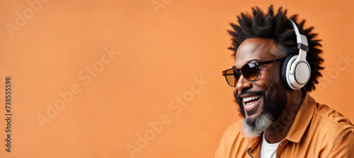 banner Portrait Of A Cheerful African American Bearded Man Listening To Music On Headphones In Studio On Orange Background