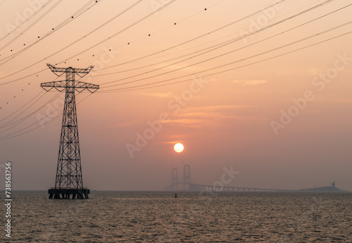 High voltage electricity tower in the ocean at sunset