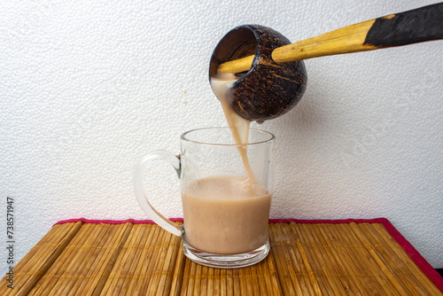 Pouring traditional African sorghum beer in a mug using a local scoop
