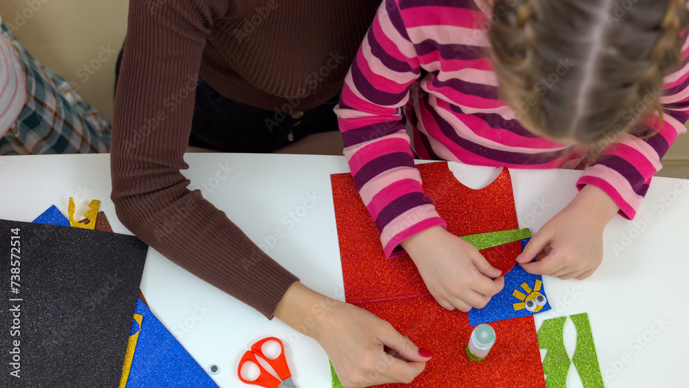 Obraz premium Close up of woman cuts with children object from colored paper.
