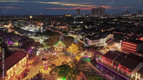 Aerial evening shot of Malacca city center, Melaka Tengah District, Malaysia. River with embankment, ancient colonial buildings with illumination in Malacca. Red sunset sky at background photo