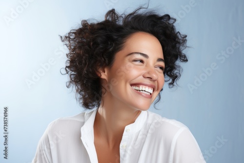 Portrait of beautiful young happy smiling woman with curly hair over blue background
