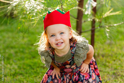 Portrait of a happy toddler girl outside in felt Christmas cracker hat photo