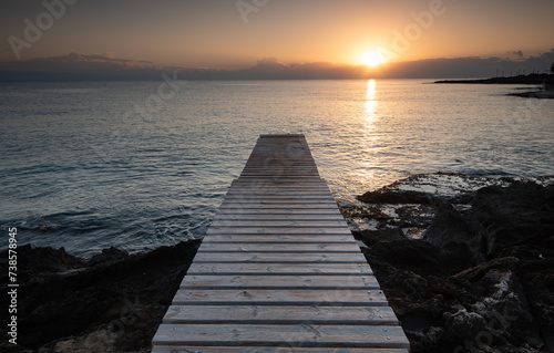 Long wooden pier in the sea at sunrise.