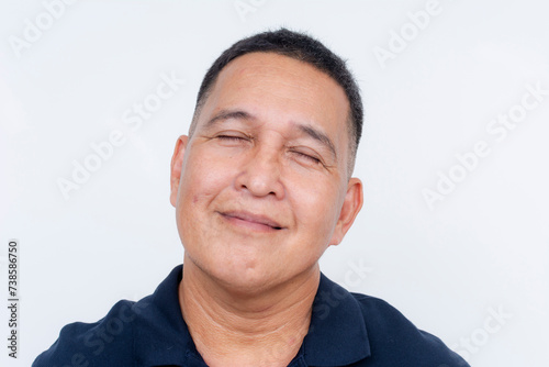 A middle-aged Asian man closes his eyes, exuding tranquility and happiness as he cherishes joyful memories or ideas.