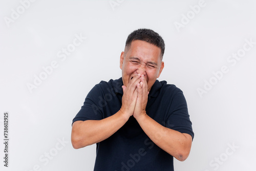 A middle-aged Asian man laughing joyously. Bursting into laughter, trying in vain to cover mouth with both hands. Isolated on a white background.