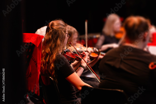 Violinist playing in strings section at music concert photo
