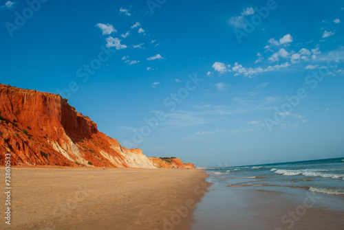 the deserted beach in front of the gigantic sand dunes on the coast of the Algarve Portugal photo