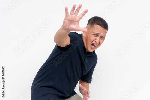 Obraz na plátně A spineless asian man in fear pleading for mercy and gesturing stop with his hand, expressing dread and panic, isolated on white