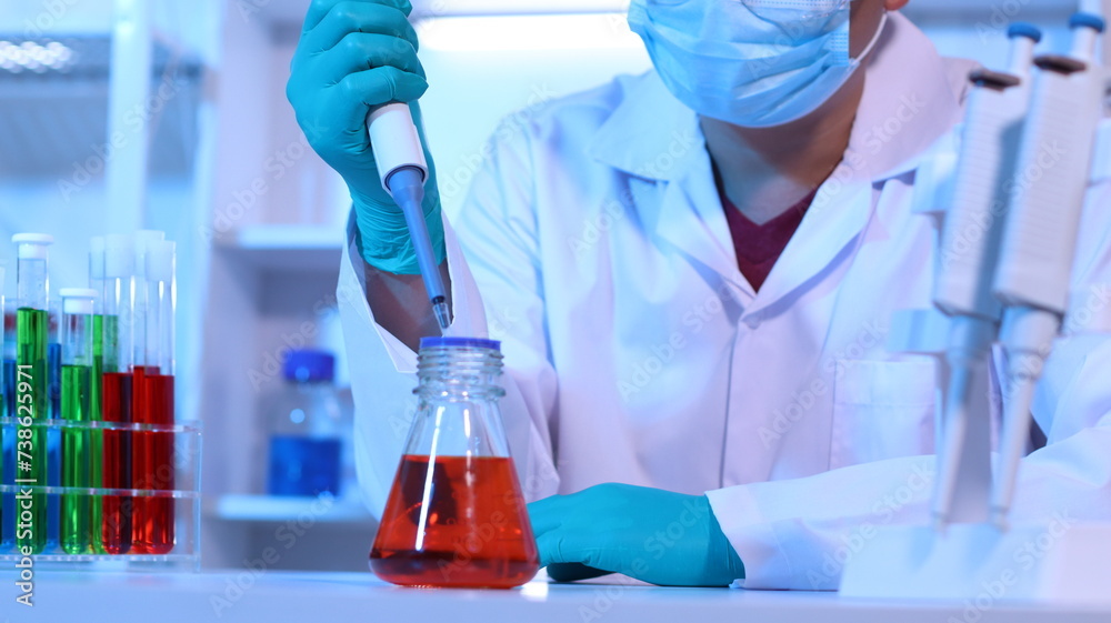 Scientists are doing research in a science lab. A medical chemist in a white coat, gloves and goggles looks at a glass tube. Compare two different liquid samples. and discuss future experiments. Scientists are doing research in a science lab. A medical chemist in a white coat, gloves and goggles looks at a glass tube. Compare two different liquid samples. and discuss future experiments.