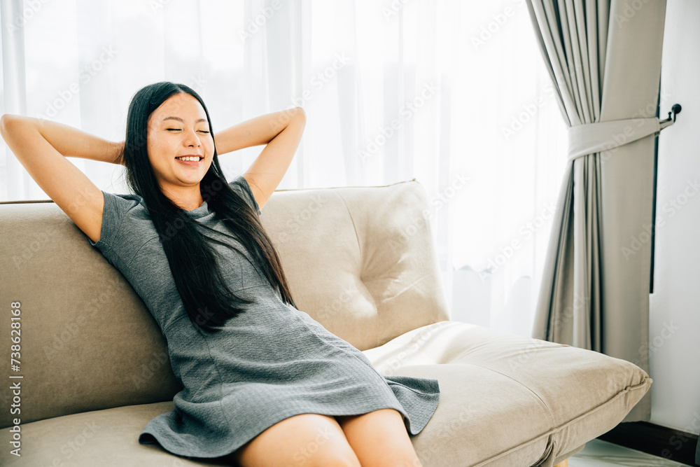 Relaxed woman on sofa hands behind head enjoys serene moment. Dreaming and finding balance in a cozy modern living room. Embracing relaxation wellbeing and mindfulness. Kick back and relax concept Relaxed woman on sofa hands behind head enjoys serene moment. Dreaming and finding balance in a cozy modern living room. Embracing relaxation wellbeing and mindfulness. Kick back and relax concept
