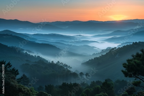 Sunrise over a misty valley, with layers of hills visible in the distance, nature landscape © arhendrix