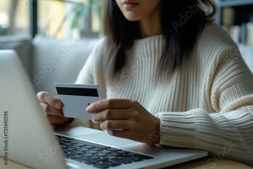 A close-up of a woman making an online purchase, entering information on her laptop and paying with a credit card