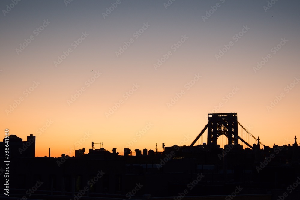 Skyline of Fort Lee with George Washington Bridge silhouetted against a sunset sky