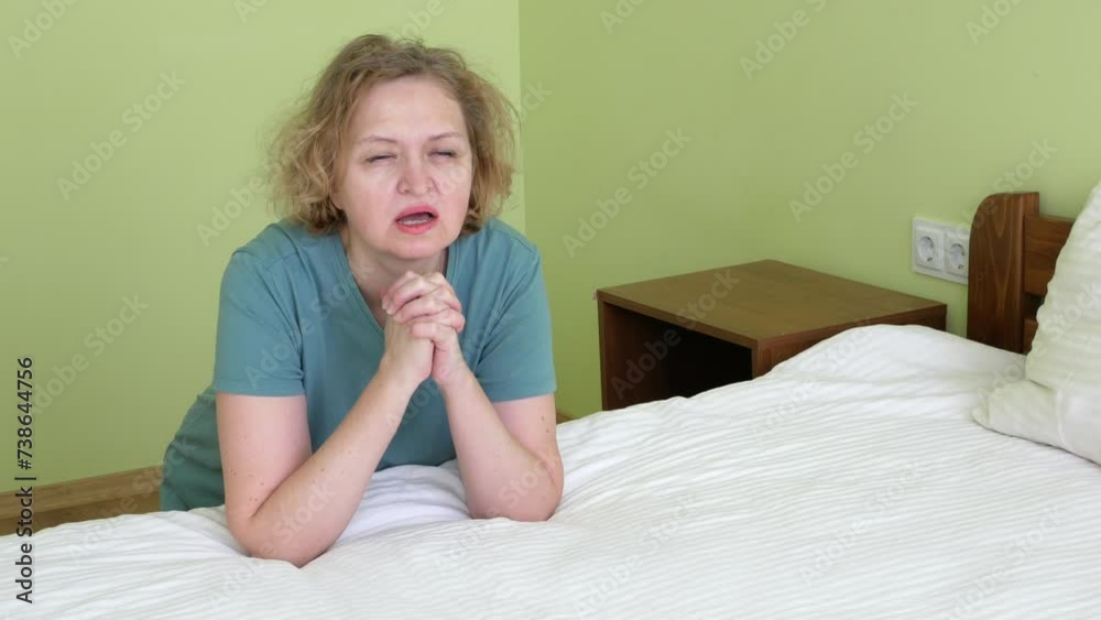 Middle aged blond European woman with curly hair with pray and worship god in her bedroom, woman praying on bed in bedroom home for hope, help or spiritual faith. God, christian Middle aged blond European woman with curly hair with pray and worship god in her bedroom, woman praying on bed in bedroom home for hope, help or spiritual faith. God, christian