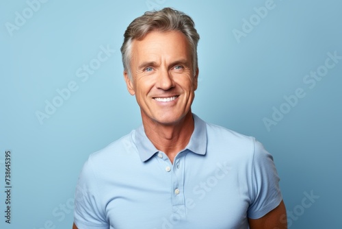 Handsome mature man in blue polo shirt on blue background.
