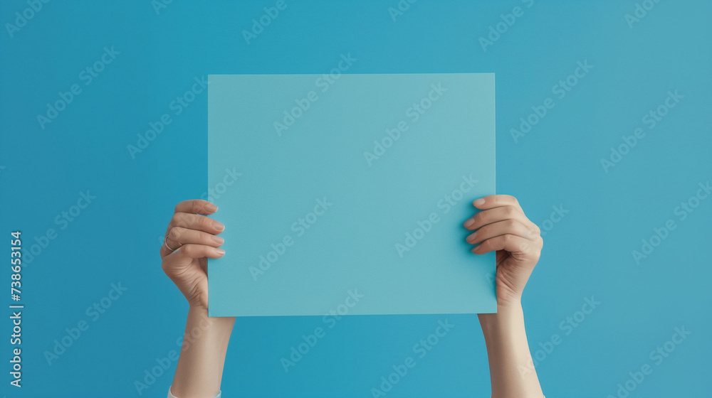 Hands holding a blank blue sheet against a blue background