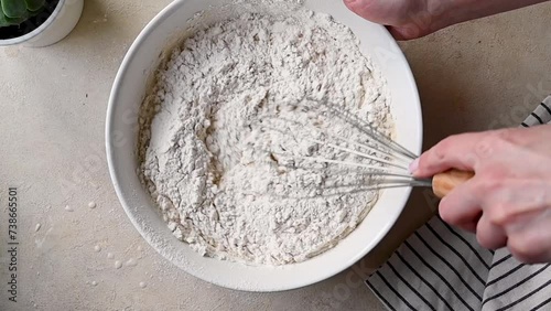 Female hands whisking flour dough batter in a bowl for pancakes or cake. photo