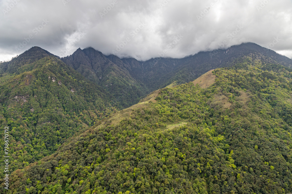 High mountains slopes covered in thick virgin forest and shrouded in cloud near the small village of senge near tawang in western arunachal pradesh, India.