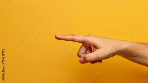 A hand pointing at something on a vibrant yellow background, with ample space for adding text or captions. photo