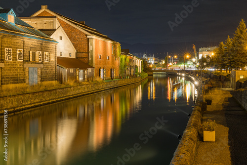 日本 北海道小樽市にある小樽運河沿いのガス灯に明かりが灯った夜景とライトアップされた石造倉庫群
