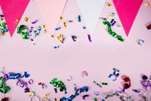 Confetti and holiday flags on pink background, festive celebration, birthday party decor, colorful pennants
