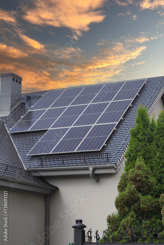 Solar panels installed on the roof of a residential building, capturing energy during a vibrant sunset