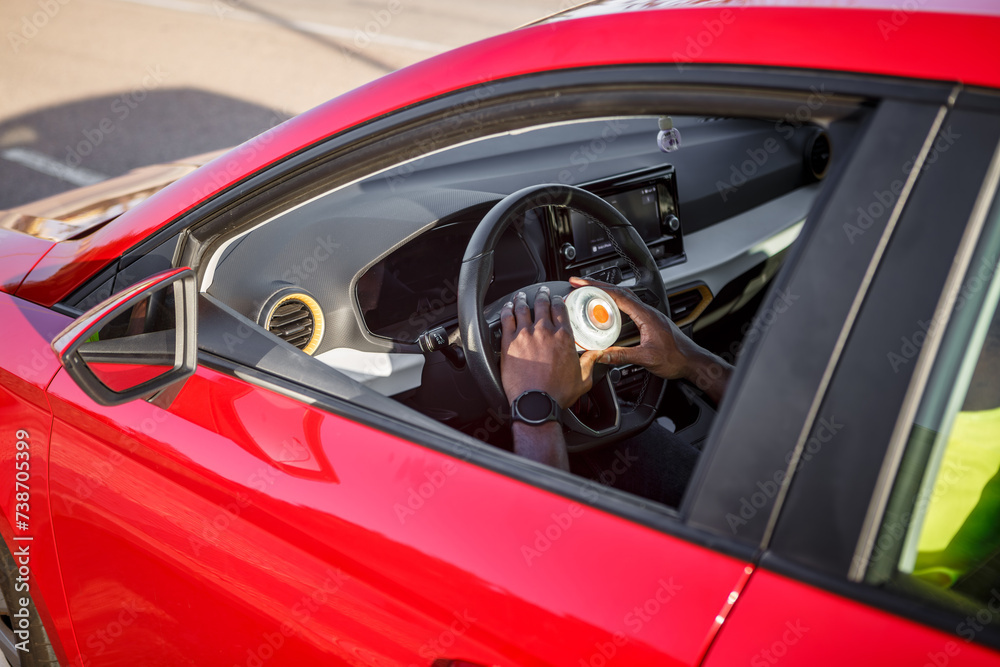 Man inside red car with emergency light on steering wheel