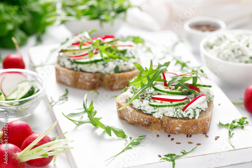 Sandwiches with rye bread toasts, cottage cheese, radish, cucumber, fresh greens and arugula for a healthy breakfast