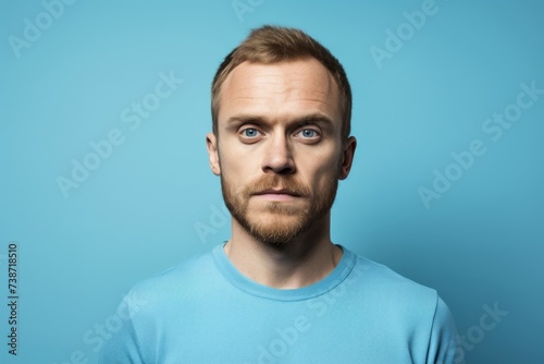 Portrait of a handsome young man with beard on blue background. © Loli