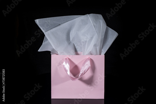 Craft paper gift bag with tissue paper isolated on a black background