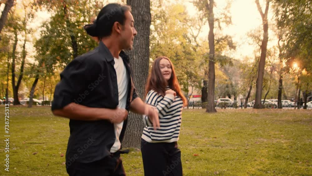 Young couple of cheerful dancers in casual clothes performing a joint dance in a city park in sunny day close up. Concept of outdoor active summer leisure Young couple of cheerful dancers in casual clothes performing a joint dance in a city park in sunny day close up. Concept of outdoor active summer leisure
