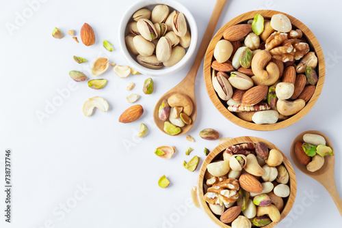 Mixed nuts in wooden bowl with spoon on white background, top view photo