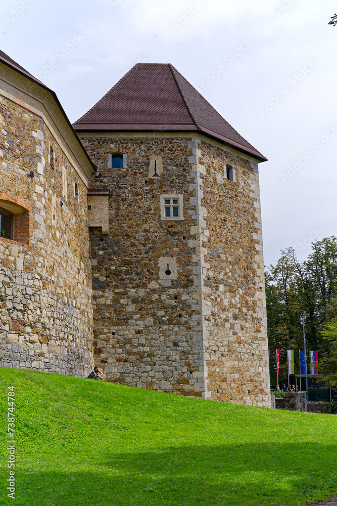Looking up stone wall and tower with loophole of Castle of Ljubljana on a cloudy summer day. Photo taken August 9th, 2023, Ljubljana, Slovenia. Looking up stone wall and tower with loophole of Castle of Ljubljana on a cloudy summer day. Photo taken August 9th, 2023, Ljubljana, Slovenia.