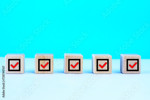  Check mark on wooden blocks, blue background with copy space.