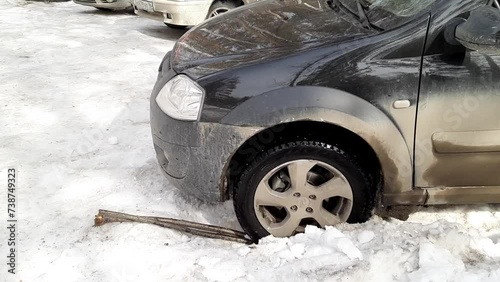 The car is stalling in the snow. A wheel is stuck in the sego photo