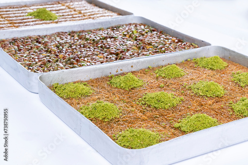 Top view of shredded phyllo dough dessert species with pistachio on trays isolated on white background. Local name is kadayıf which is a traditional Turkish cuisine dessert with pistachio and sherbet. photo