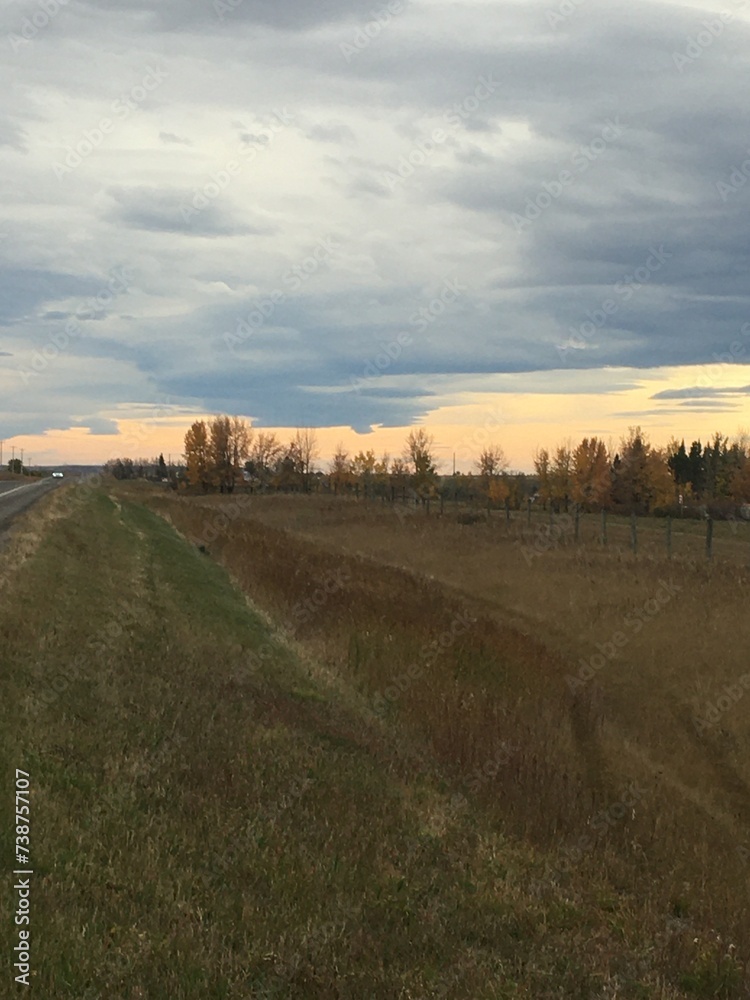 The stretching arm of a Chinook cloud on the Alberta Prairie accompanied by a strip of setting sun. 