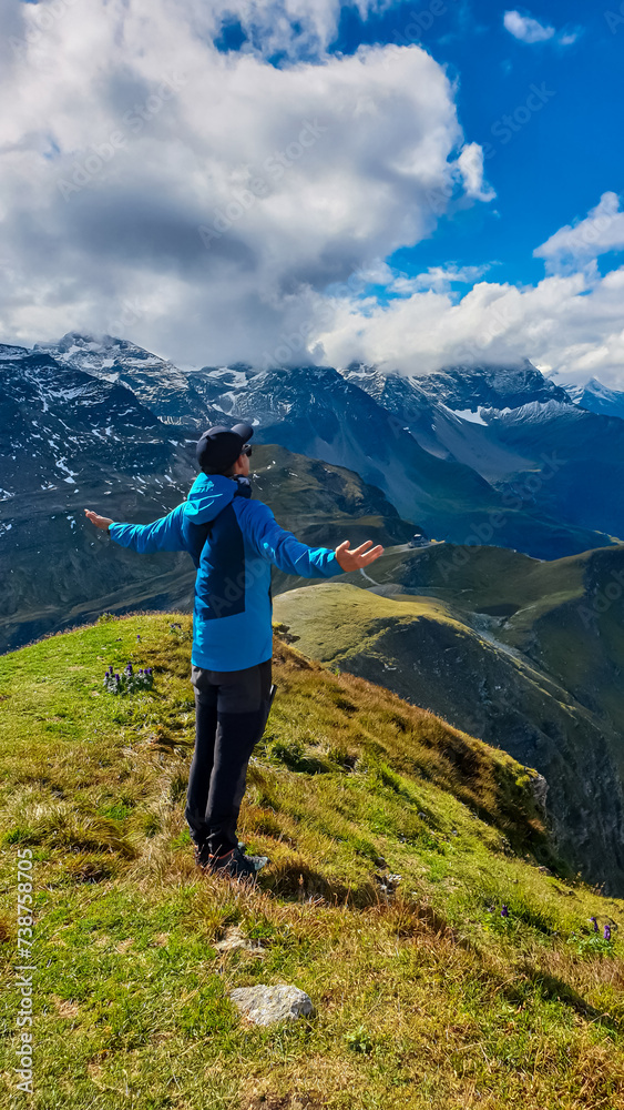 Hiker man on top of mount Greilkopf with scenic view of majestic mountain peaks of Glocker group, High Tauern National Park, Carinthia Salzburg, Austria. Wanderlust at Hagener Huette, Austrian Alps