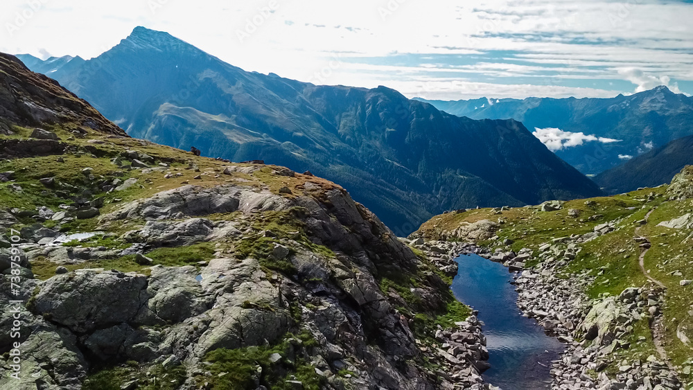 Small lake surrounded by field of rocks in High Tauern National Park, Carinthia, Austria. Idyllic hiking trail from Hannoverhaus to Hagener cottage in Austrian Alps in summer. Hike paradise Mallnitz