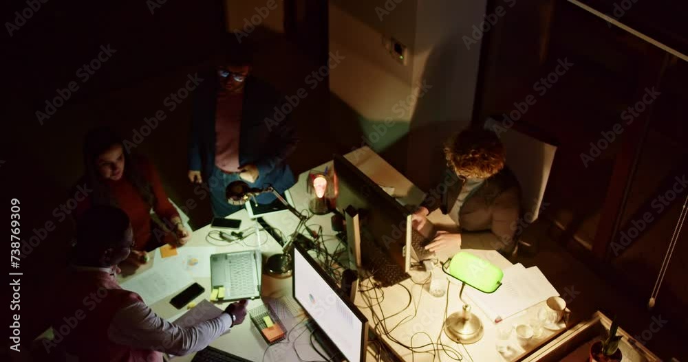 Mixed race, multi generational team collaborates, solving final project tasks and exhibiting a unified commitment to achieving project success and it's deadline.