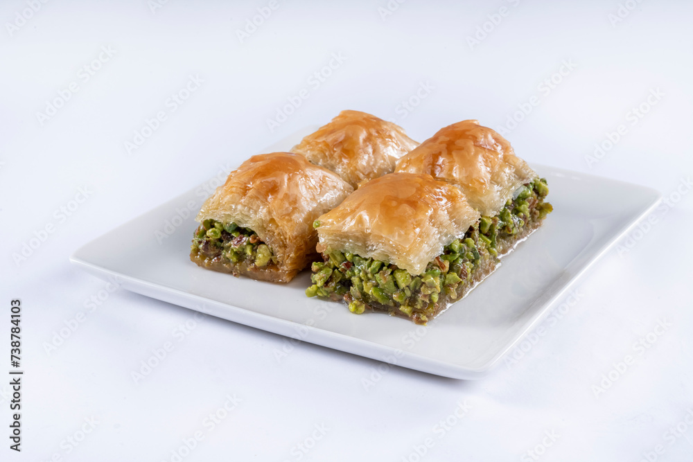 Top view of square baklava with pistachio on white plate isolated on white background. Top view of square baklava with pistachio on white plate isolated on white background.