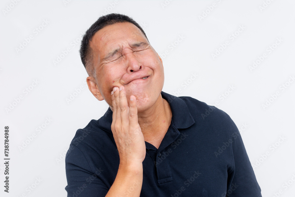 A middle aged Asian man with experiencing excruciating pain, holding his cheek due to a toothache. Potential exposed nerve in the tooth. A middle aged Asian man with experiencing excruciating pain, holding his cheek due to a toothache. Potential exposed nerve in the tooth.