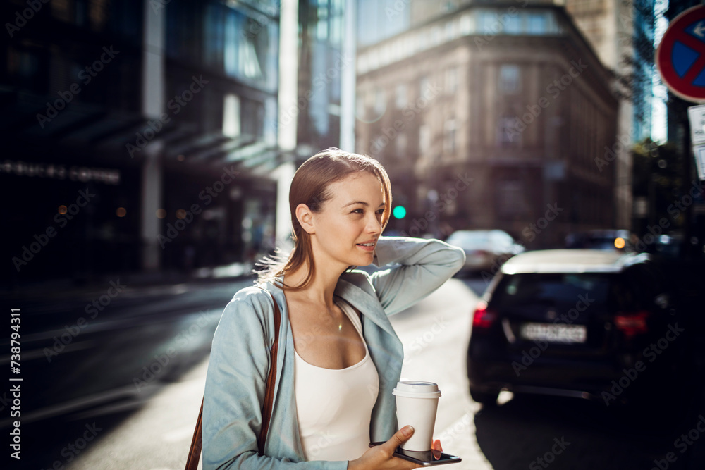 Fototapeta premium Young adult woman using her smart phone while commuting in the city