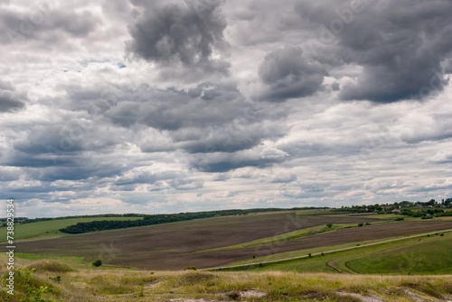 Green landscape of farmland against a stormy sky in the spring season. Advertising space concept.