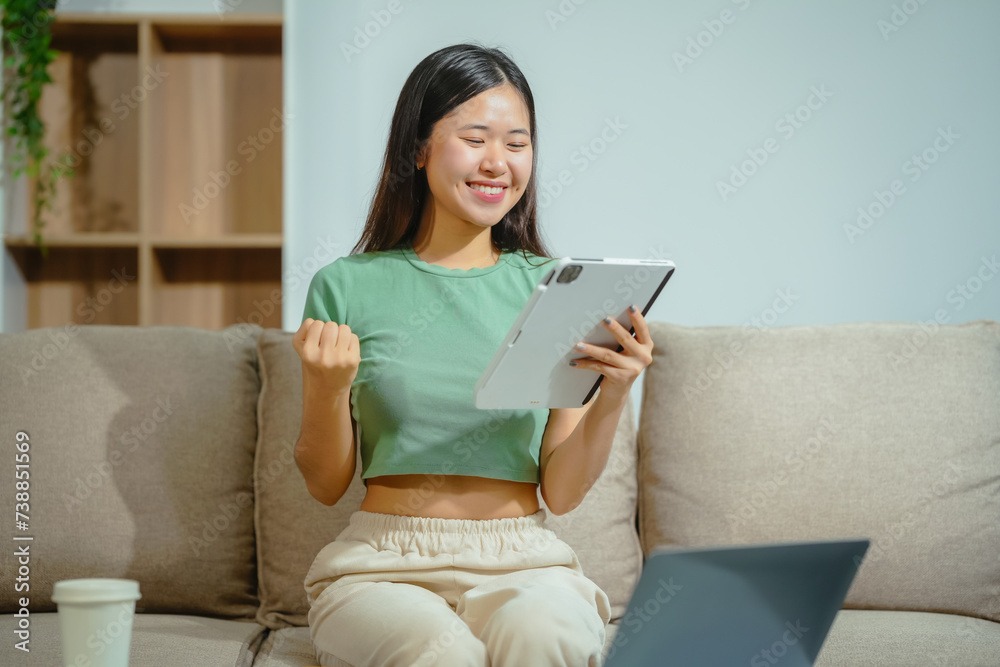 young Asian girl engages in online learning, doing homework on her sofa in the living room. video classes, combining comfort and education at home. young Asian girl engages in online learning, doing homework on her sofa in the living room. video classes, combining comfort and education at home.