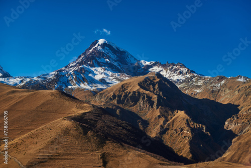 A mesmerizing tableau of mountain peaks rising above the world  bathed in the soft light of a clear blue sky.