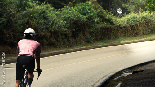 cyclist man descending a hill and taking a turn down a street surrounded by nature in colombia