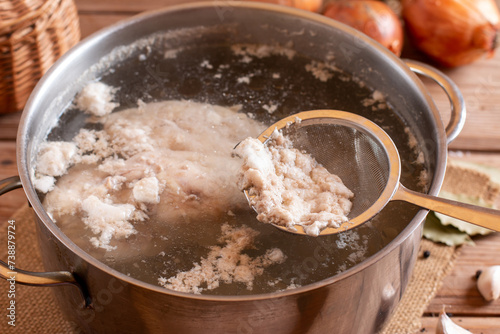 The boiling broth is filled with white bubbles floating in a pot. Some of the water sprang up with heat. Remove the foam