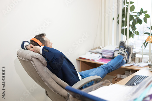 happy young business man with headphones having break in modern office 